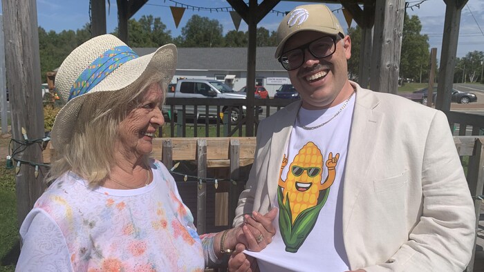 Un homme et une femme, avec le sourire aux lèvres, dehors.