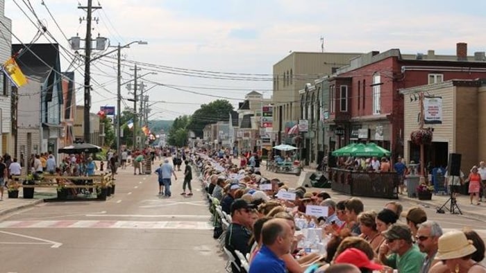 Une longue table au milieu de la rue principale de Shediac, au Nouveau-Brunswick, avec des centaines de personnes attablées, prête à manger du homard.