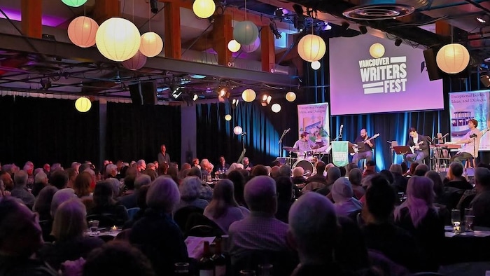 Des musiciens jouent sur une sc&egrave;ne devant un public.