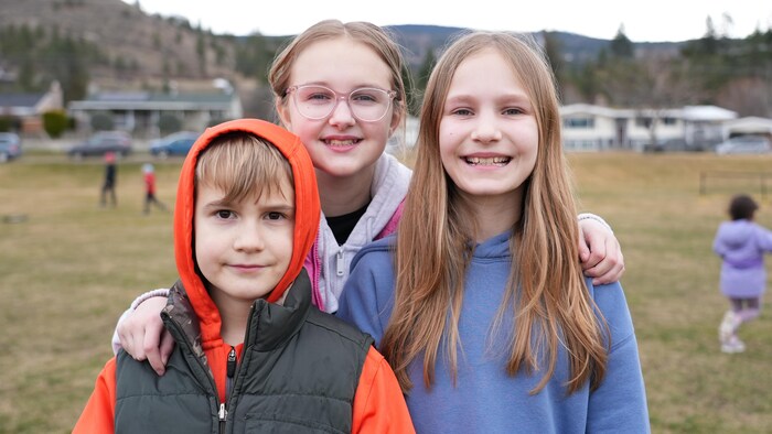 Dominic Jung, Elizabeth Jung et Gina Barth dans la cour d’école d’Entre-Lacs à Penticton, le 7 mars 2026.