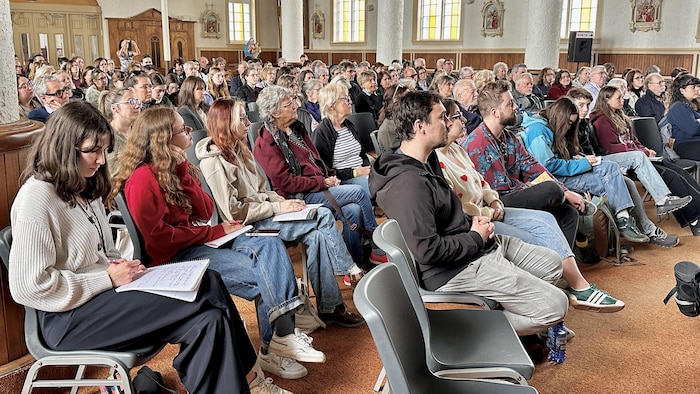 Des gens dans une église qui écoutent une conférence.