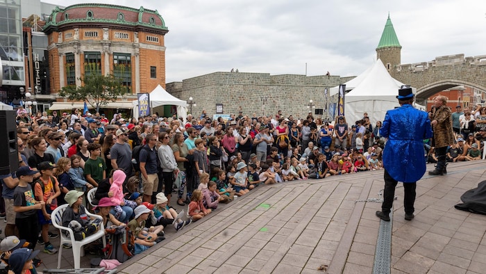 Un magicien parle à la foule à Place d'Youville. 