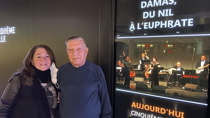 Un homme et une femme debout devant une affiche de spectacle