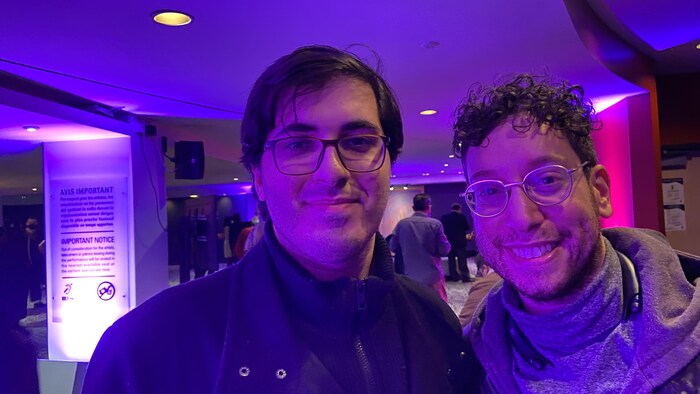 Deux hommes debout dans le hall d’une salle de spectacle