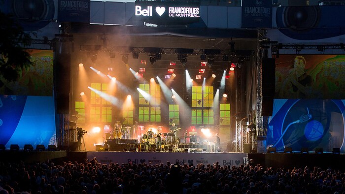 La foule est devant une scène avec des musiciens et des musiciennes.