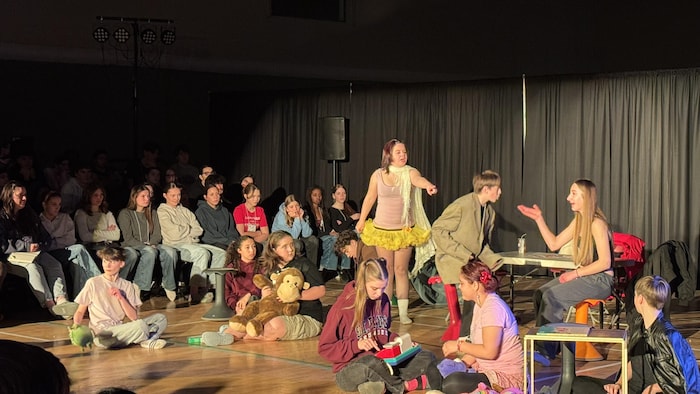 De jeunes comédiens en train de se produire sur scène devant un public.