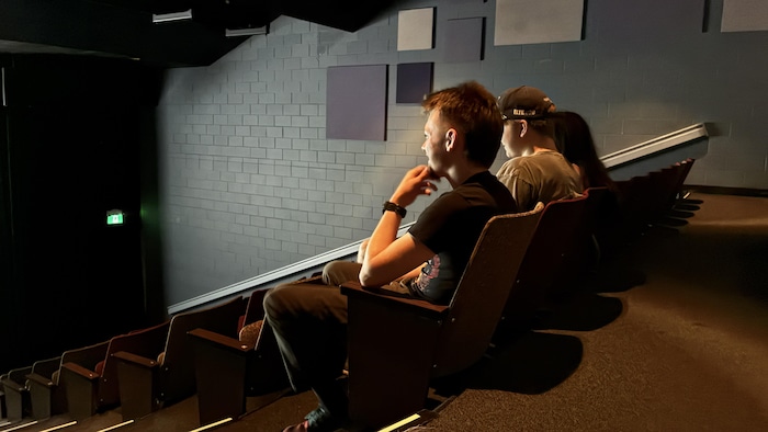 Les trois adolescents regardant leur production dans une salle de cinéma.