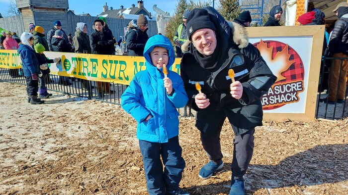 Un homme et un jeune garçon avec une tire d'érable le 26 février 2023 à Winnipeg.