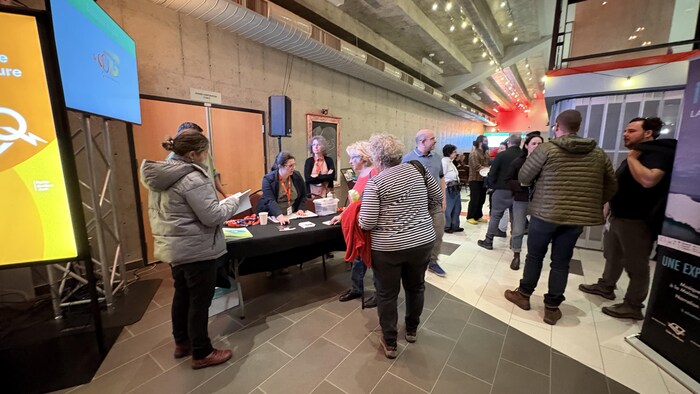 Un hall avec plusieurs kiosques et des personnes en discussion.