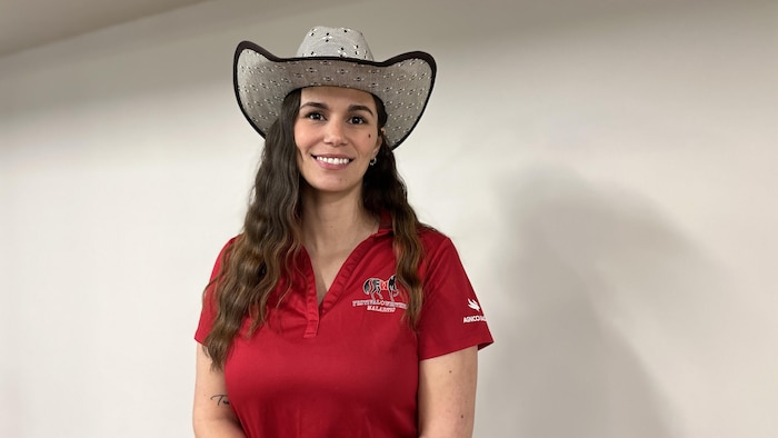 Carolann Chabot pose vêtue d'un polo du Festival western et un chapeau de cowboy, souriante.