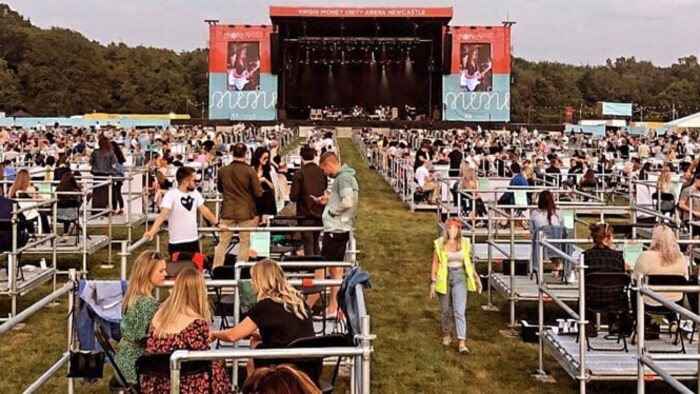 Plusieurs personnes se trouvent sur des installations métalliques devant une scène de spectacle.