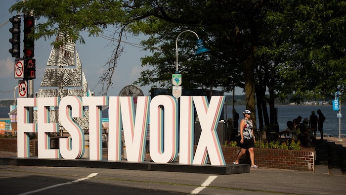 Une femme marche près d'une enseigne du FestiVoix.