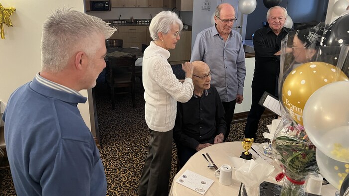 Des gens fêtent un homme assis.