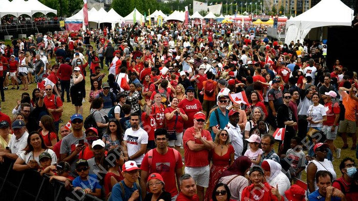 Ang mga tao iwinawagayway ang maple leaf, pumapalakpak at nakatingin sa entablado.