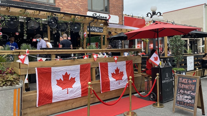 Some people take place on a terrace on the by market by decorated with Canada flags. where celebrate canada's day national