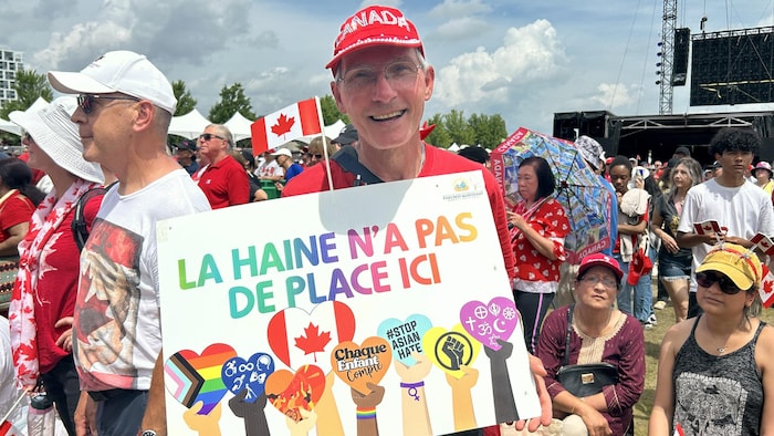 A man holding a sign in a crowd at Canada's Day. canada day marked "canadian pride"