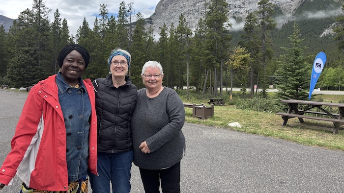 Annie Adolphine Moqé, Véronique Lavoie et Jeanne-D’Arc Mailloux sourient devant les montagnes Rocheuses.