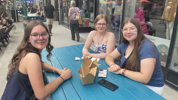 Trois filles mangent une poutine.