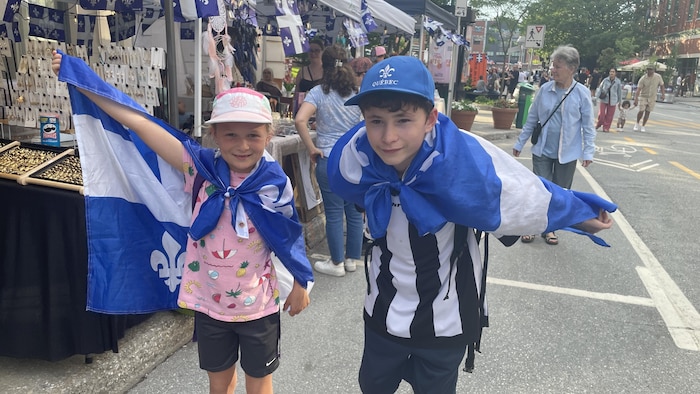 Deux personnes avec des drapeaux du Québec autour d'eux.