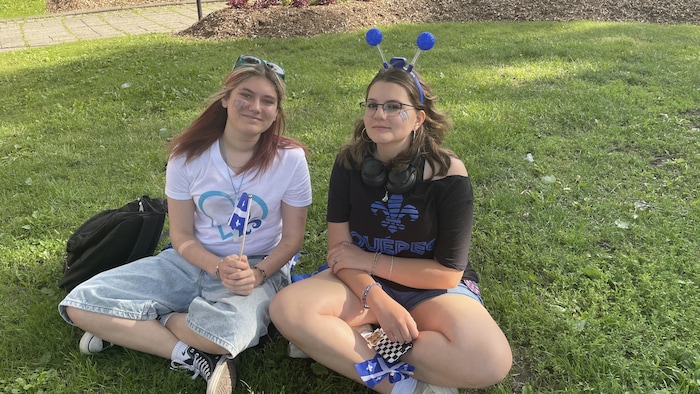 Deux filles sont assises dans l'herbe.