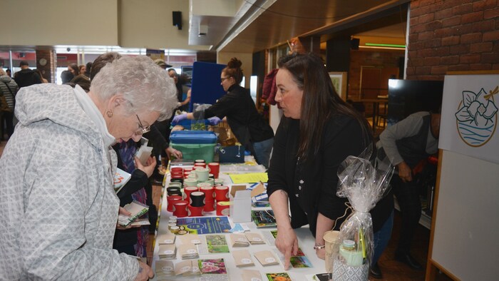 Une dame examine une table couverte de sachets de semences durant un événement.