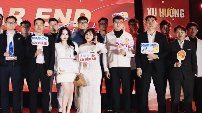 À gauche, le PDG de HTV Network, NGO Anh Tan, tient un écriteau en vietnamien où on peut lire "un chiffre d'affaires record". Son collègue, à droite, en tient un autre où on peut lire "un chiffre d’affaires de 100 milliards".