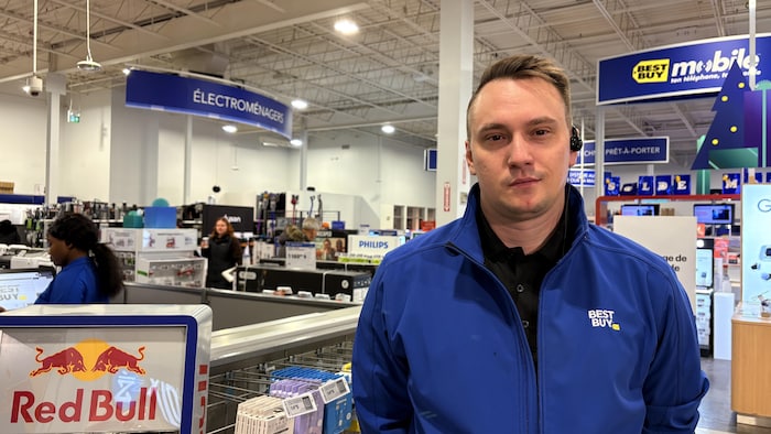 Un employé pose dans un commerce d'électronique.