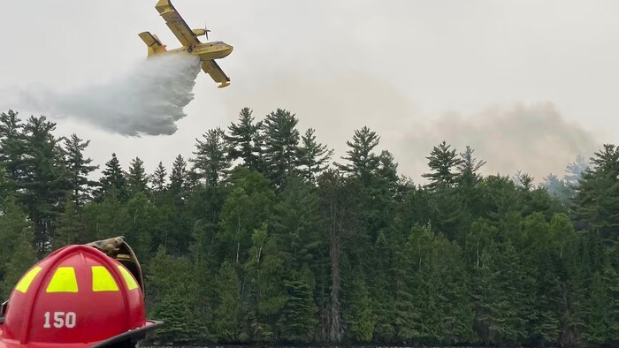 Un bombardier d'eau largue de l'eau sur un incendie.
