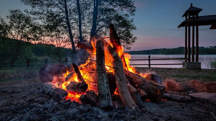 A fire of joy on the edge of a twilight lake, summer.