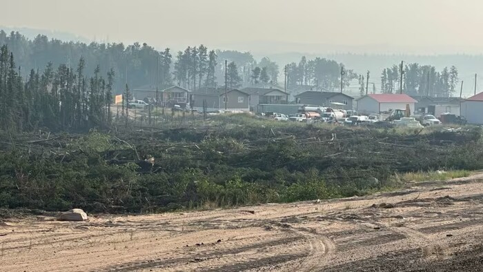Quelques maisons peu visibles à cause de la fumée du feu de forêt proche de la communauté.