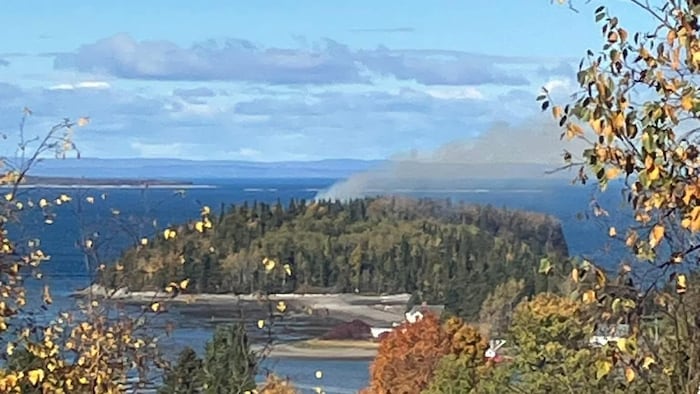 Une île d'où s'échappe un panache de fumée.