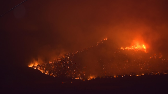 Des flammes s’attaquant à une montagne pendant la nuit.
