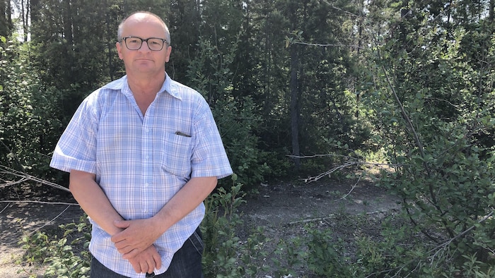 Un homme pose devant la forêt.