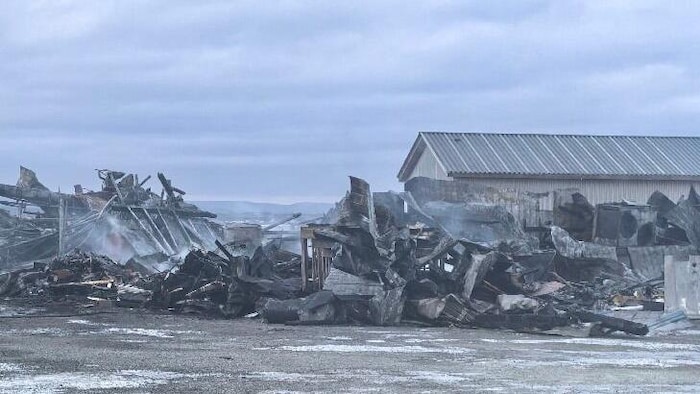 Des restes noircis et encore fumants d'un bâtiment.