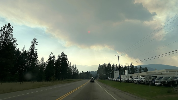 Vue fuyante d'une route avec une seule voiture, la majorité du cadre étant rempli par un nuage de fumée dense.