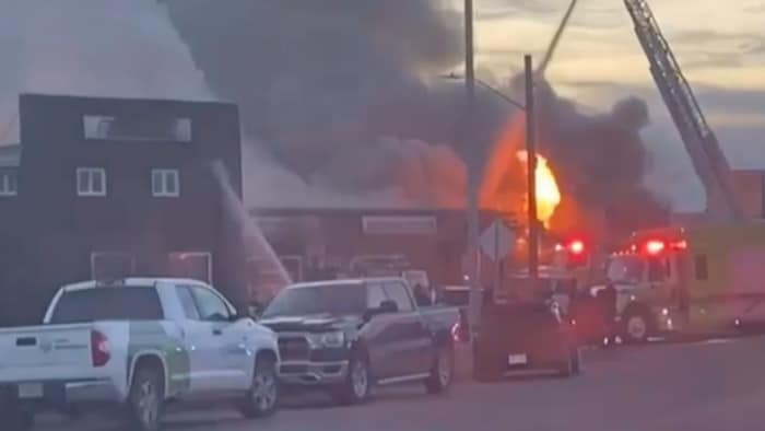 Un bâtiment avec des flammes et un panache de fumée s'en dégage. 