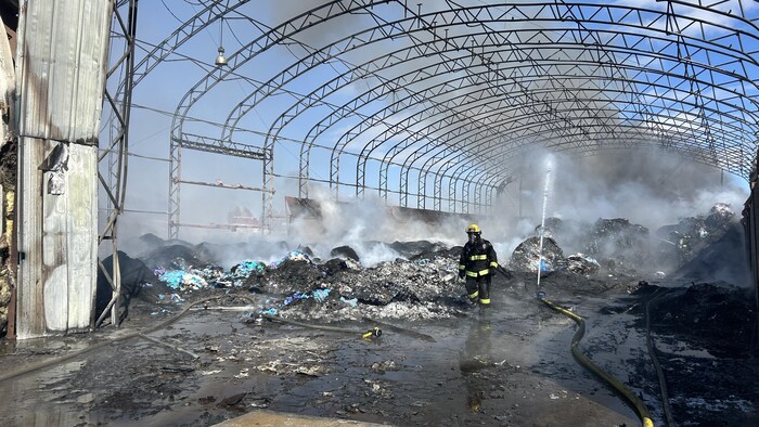 Un pompier au milieu d'un entrepôt en ruine.