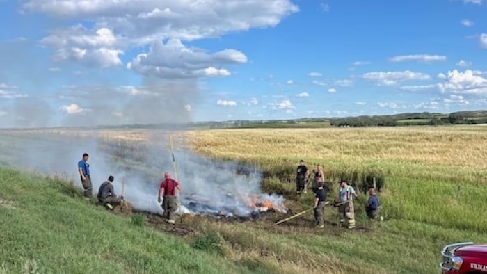 Des pompiers volontaires du Service d'incendie de Macklin s'occupent d'un feu de balles de foin. 