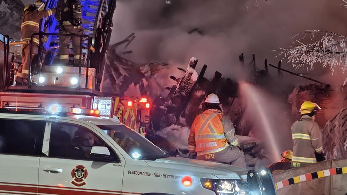 Des pompiers envoient de l'eau sur la structure calcinée de l'hôtel Malwin.