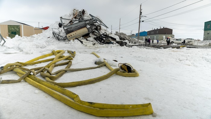 Une lance à eau devant un amas de ferraille et de neige.