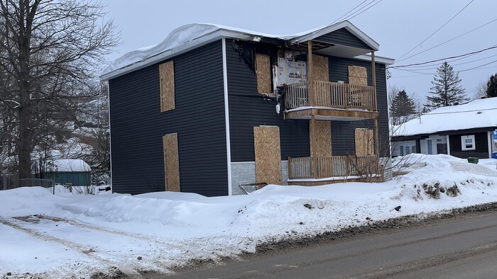 Un édifice incendié aux fenêtres placardées en hiver.