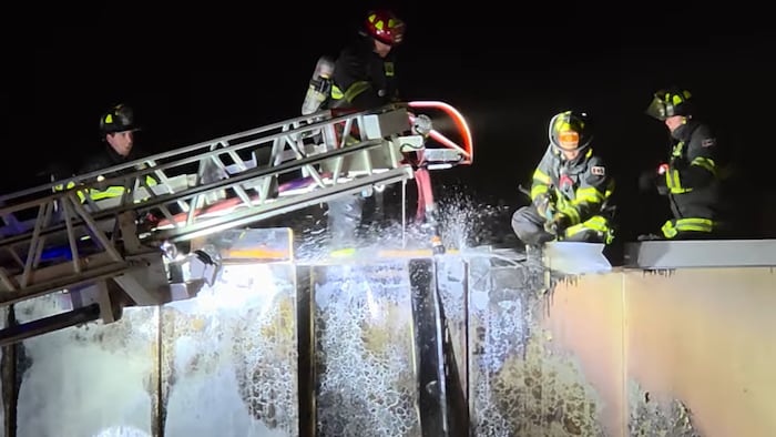 Des pompiers s'activent sur le toit d'un bâtiment. 