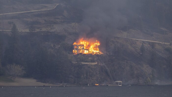A house that takes fire next to a lake.