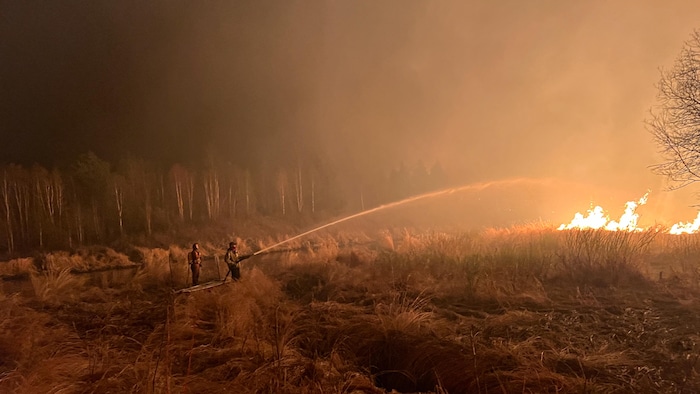 إطفائيان يكافحان أحد حرائق الغابات في ألبرتا في 7 أيار (مايو) 2023.