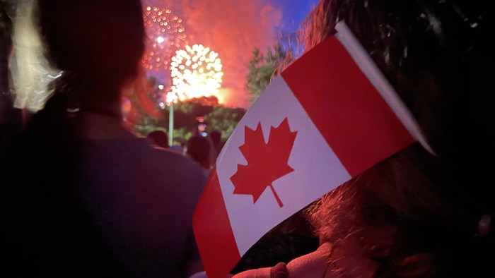Des feux d'artifices en arrière plan d'un drapeau du canada.