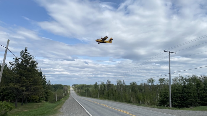 Un avion-citerne passe au-dessus d'une route.