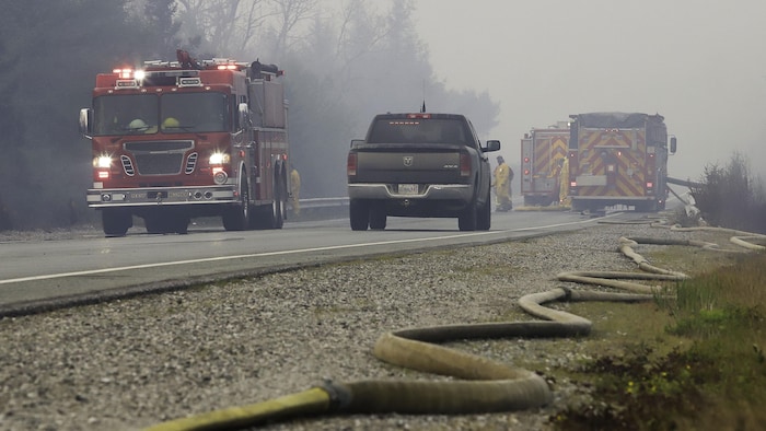 Un tuyau d'incendie repose le long de la route 103 alors que les équipes de pompiers travaillent sur des feux de forêt près de Shelburne, Nouvelle-Écosse.