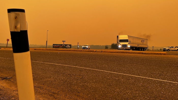 Des voitures et un semi-remorque dans une atmosphère enfumée sur la route, le ciel est jaune, le 18 mai 2023.