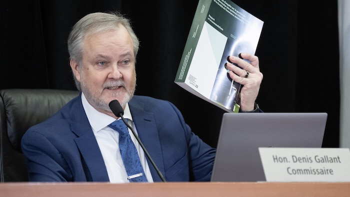 Le commissaire Gallant tient dans ses mains le rapport de près de 600 pages de la commission.