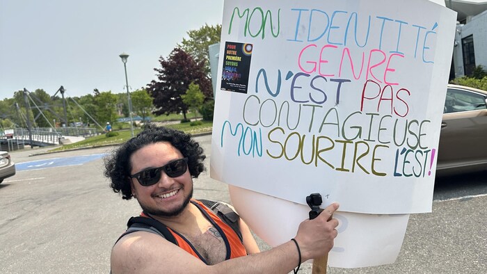 Andy Guerrero avec une pancarte, sur laquelle il est écrit: «Mon identité de genre n'est pas contagieuse, mon sourire l'est»